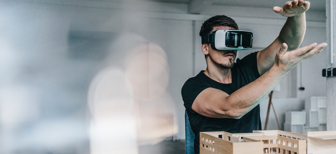 A man wears a headset to augment visual reality with hand gestures. 